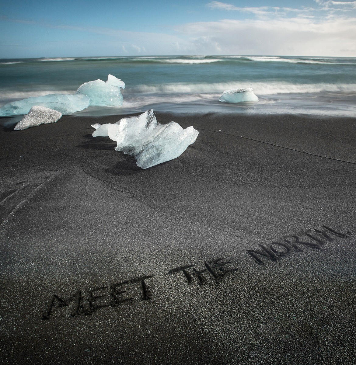 Meet the North written in the black sand beach of southern Iceland