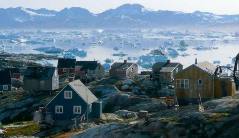 A greenlandic town with sea ice in the background